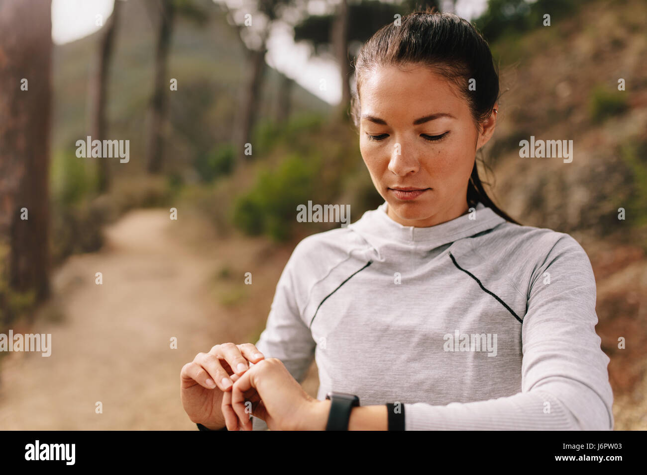 Controllo femmina progressi fitness sul suo orologio intelligente. Runner Fitness utilizzando app per monitorare le prestazioni di allenamento, permanente, mentre all'esterno su countr Foto Stock