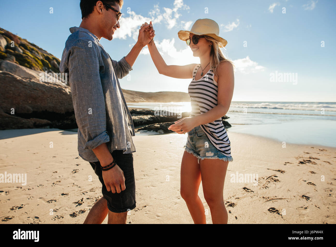 Colpo di giovane uomo e donna balli sulla spiaggia un giorno d'estate. Romantico giovane coppia danzante sulla spiaggia. Foto Stock