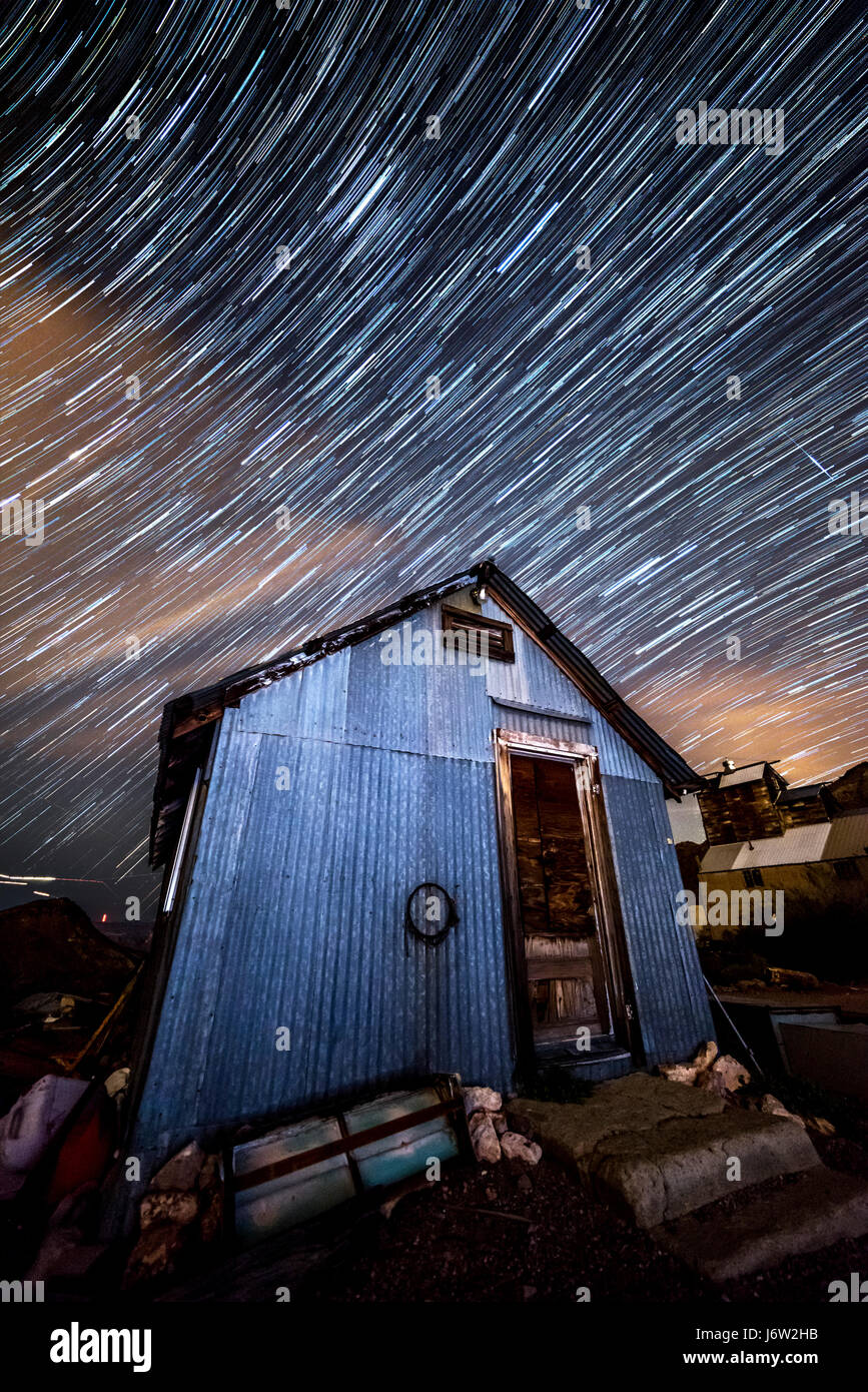 Star trail fotografia cattura il percorso delle stelle distanti incorniciato contro una vecchia capanna minimg come la terra ruota. Foto Stock