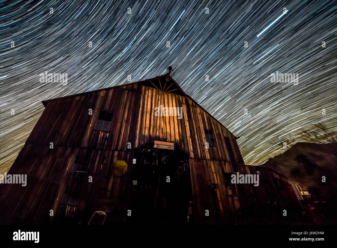 Star trail fotografia cattura il percorso delle stelle remote su un vecchio granaio di botte come la terra ruota. Foto Stock