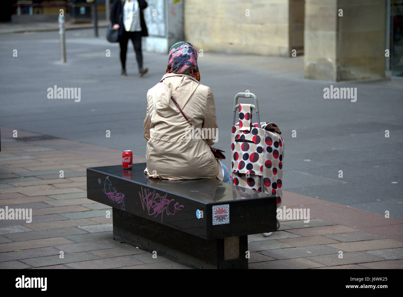 Cityscape individuo seduto con possibile coca cola hijab sciarpa Foto Stock