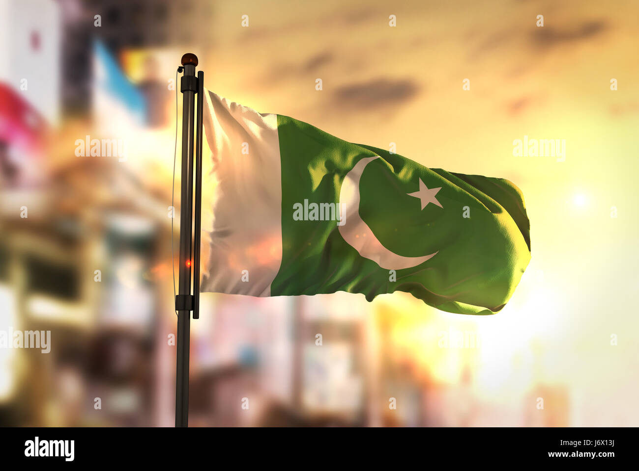 Bandiera del Pakistan contro città sfondo sfocato di Sunrise retroilluminazione Foto Stock
