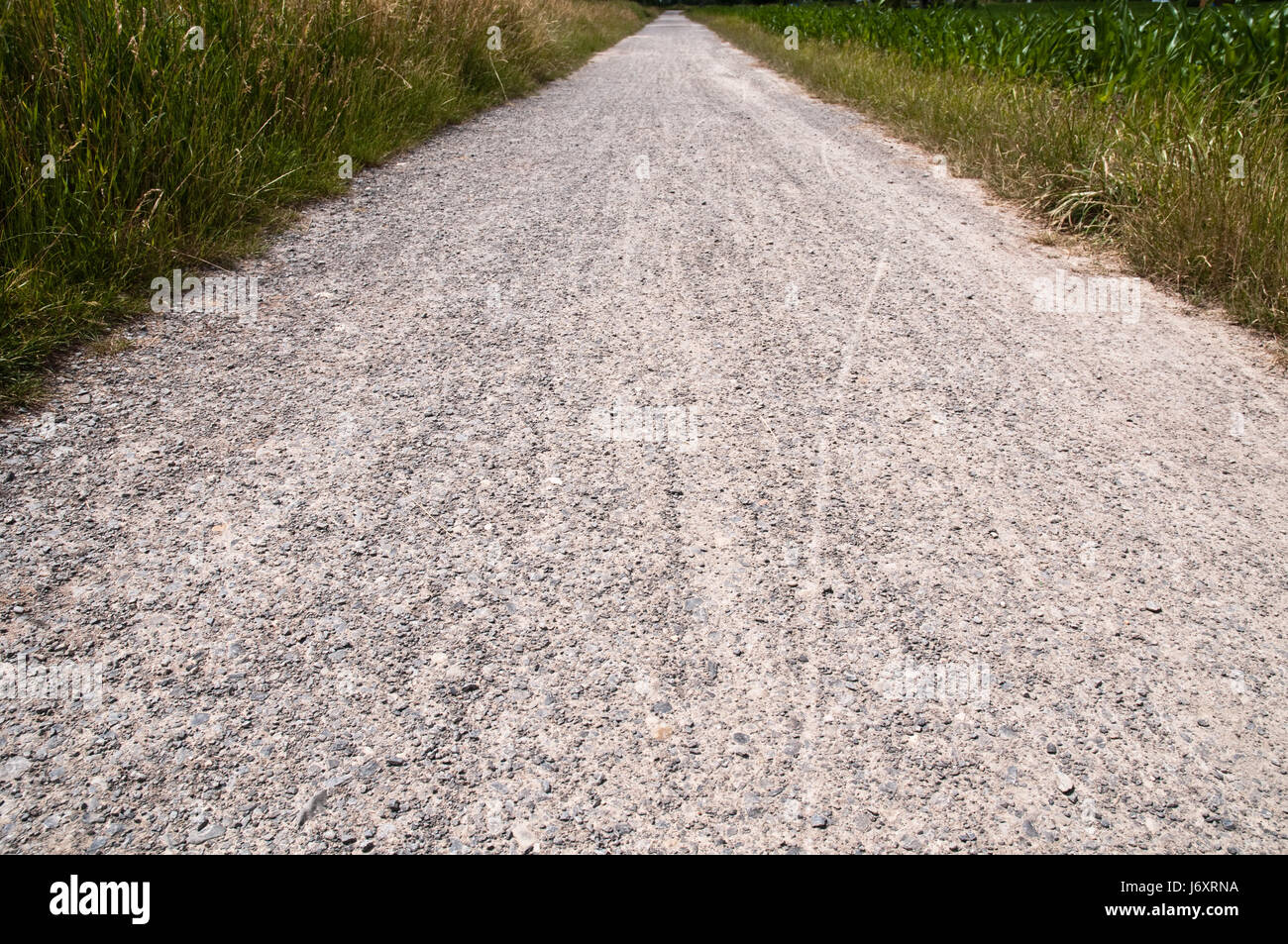 Strada sterrata larghezza lungo lontano lunghezza percorso più lungo via prato ghiaia sassoso in primo piano Foto Stock