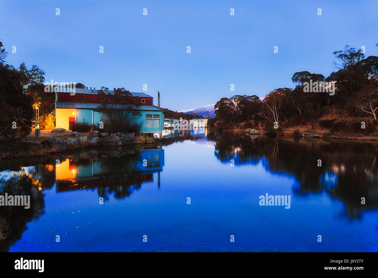 Appartata di alta montagna Lago Crackenback in THredbo valle di Snowy Mountains National Park all'alba quando il cielo blu riflette ancora in acque con hil Foto Stock