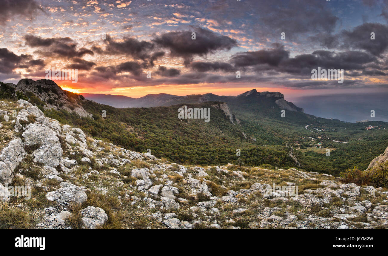 Con sunrise thunderclouds sopra il mare e le montagne Foto Stock