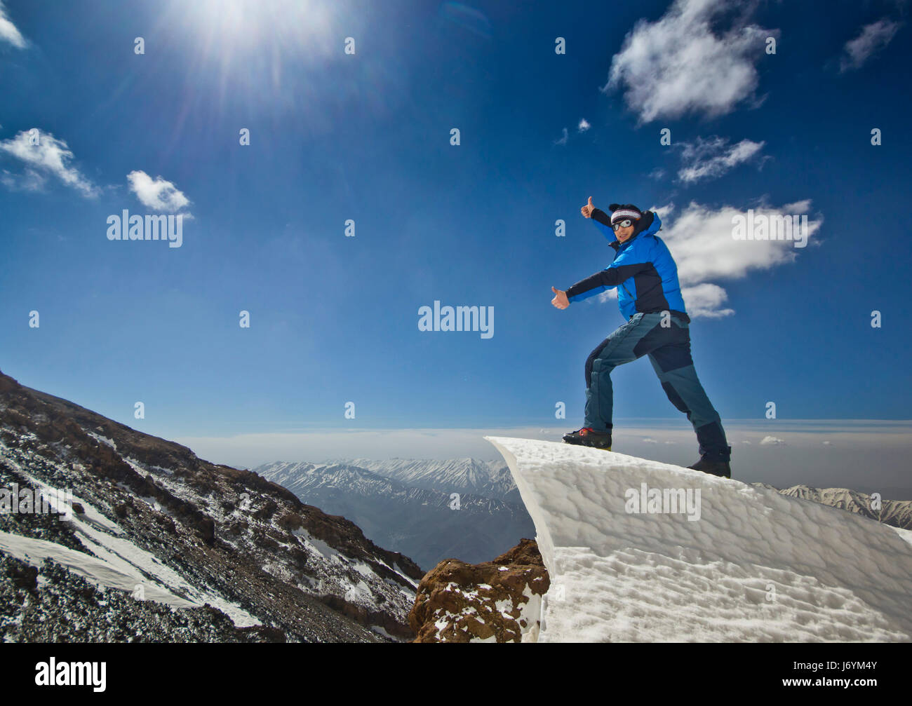Uomo in piedi su un cornicione di neve in montagna sunrise Foto Stock