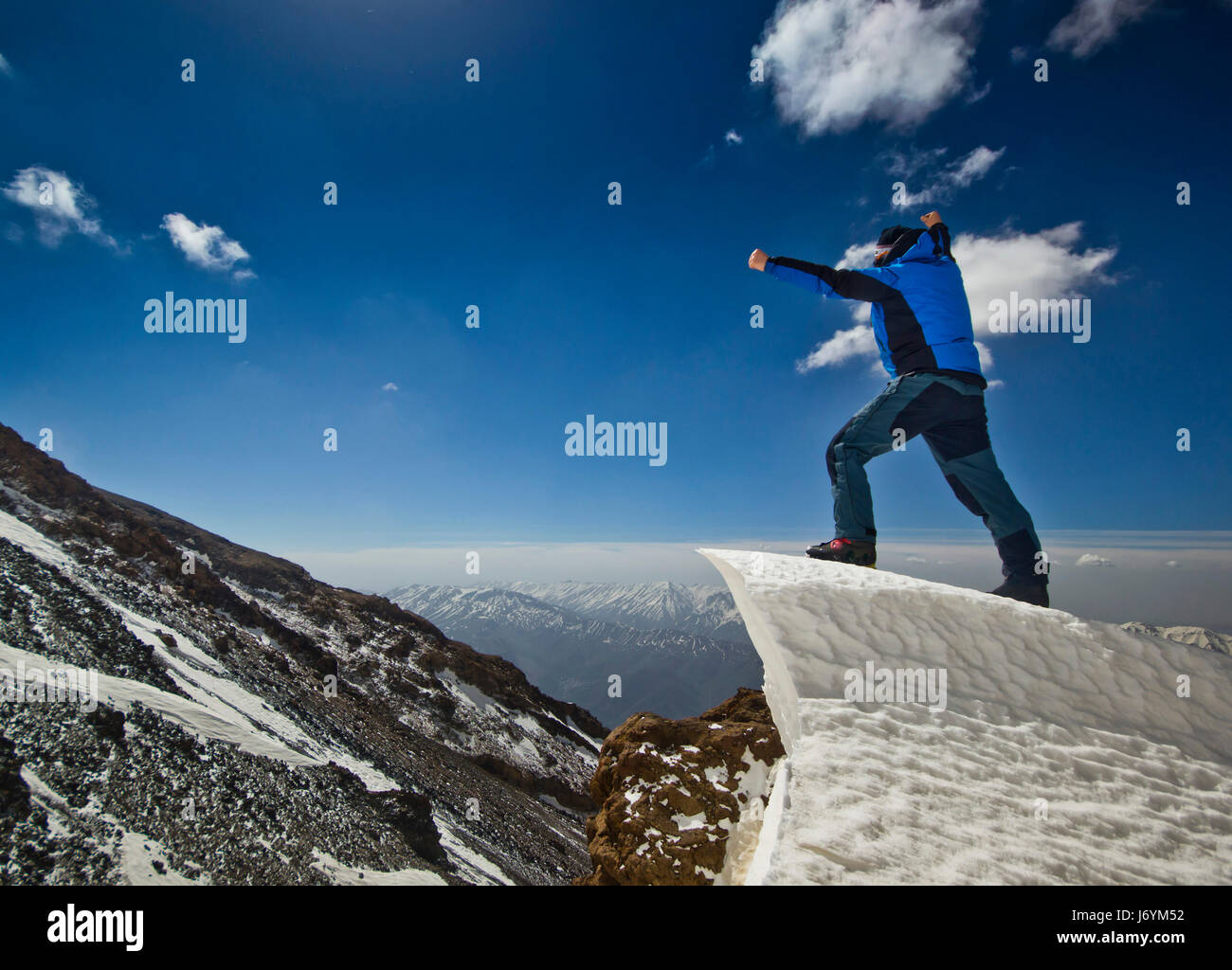 Uomo in piedi su un cornicione di neve in montagna sunrise Foto Stock
