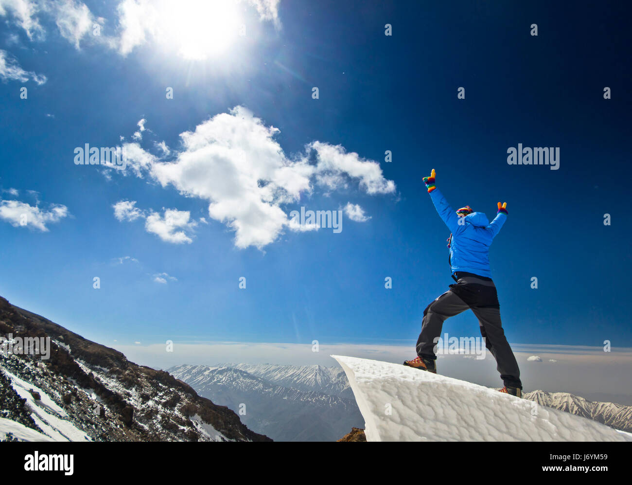Uomo in piedi su un cornicione di neve in montagna sunrise Foto Stock