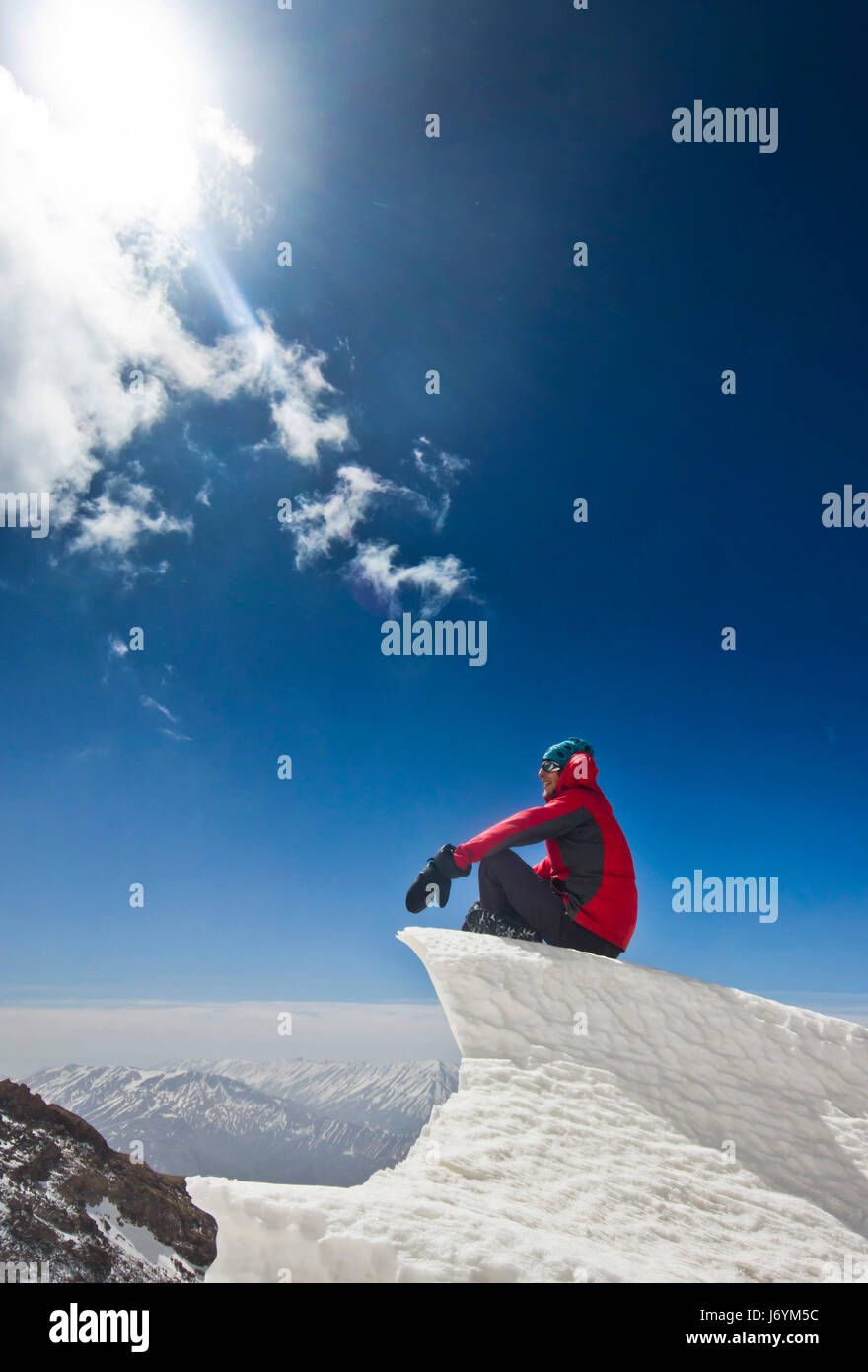 Uomo seduto su un cornicione di neve in montagna sunrise Foto Stock