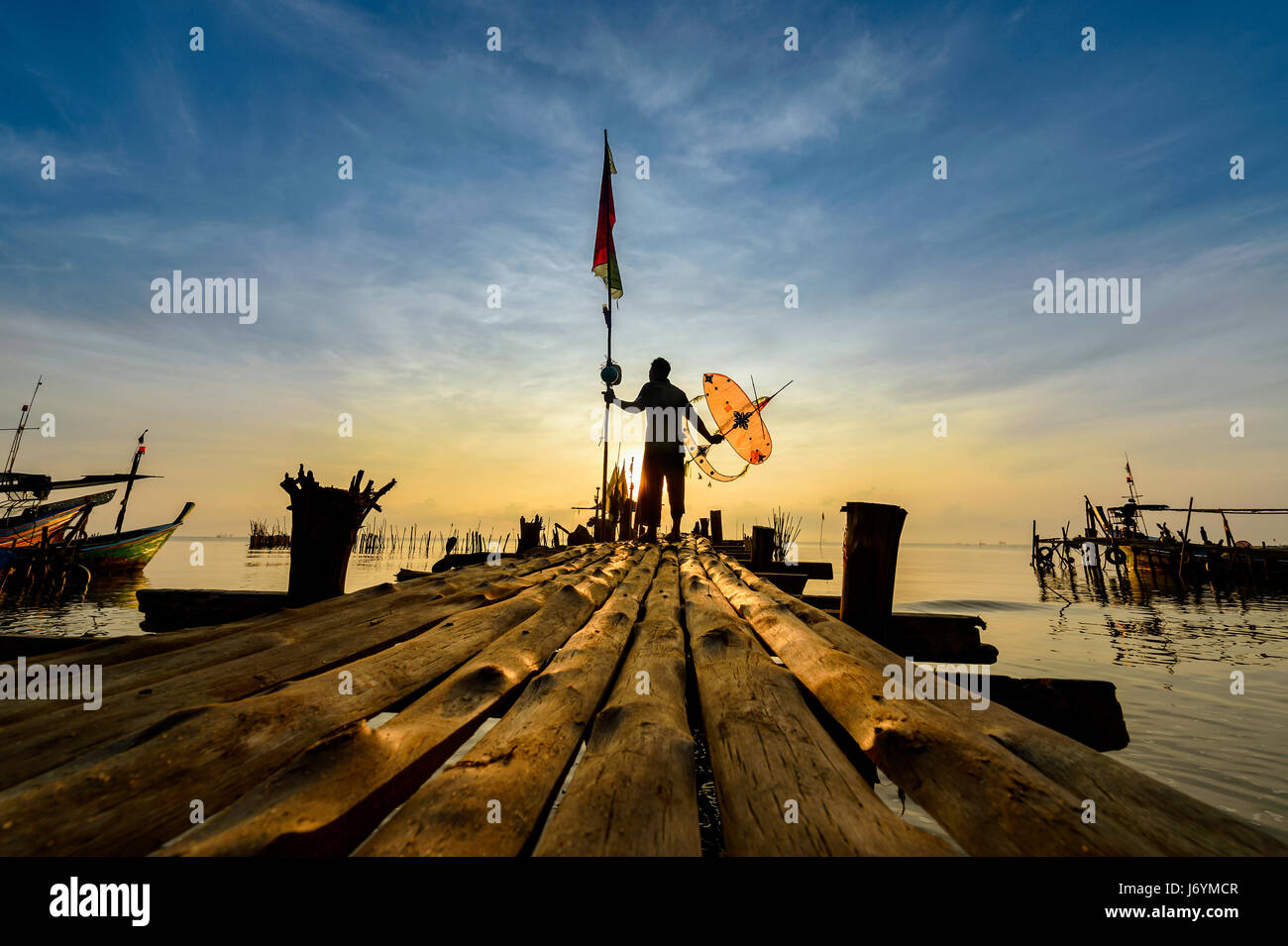 Silhouette di un pescatore in piedi sul molo, Thailandia Foto Stock