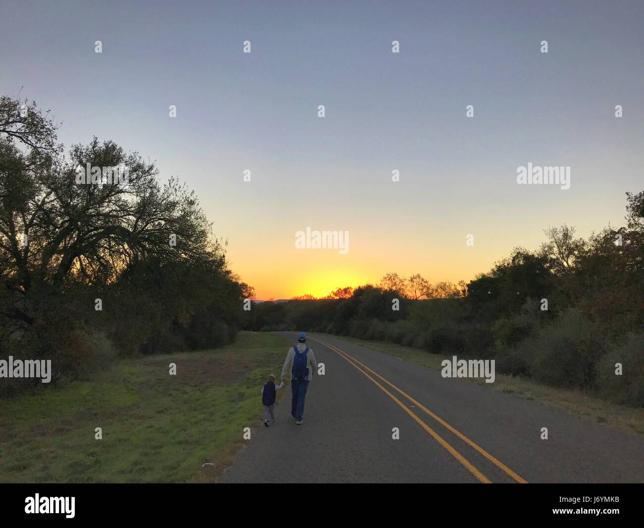 Padre e figlio camminano lungo una strada, Texas, Stati Uniti Foto Stock