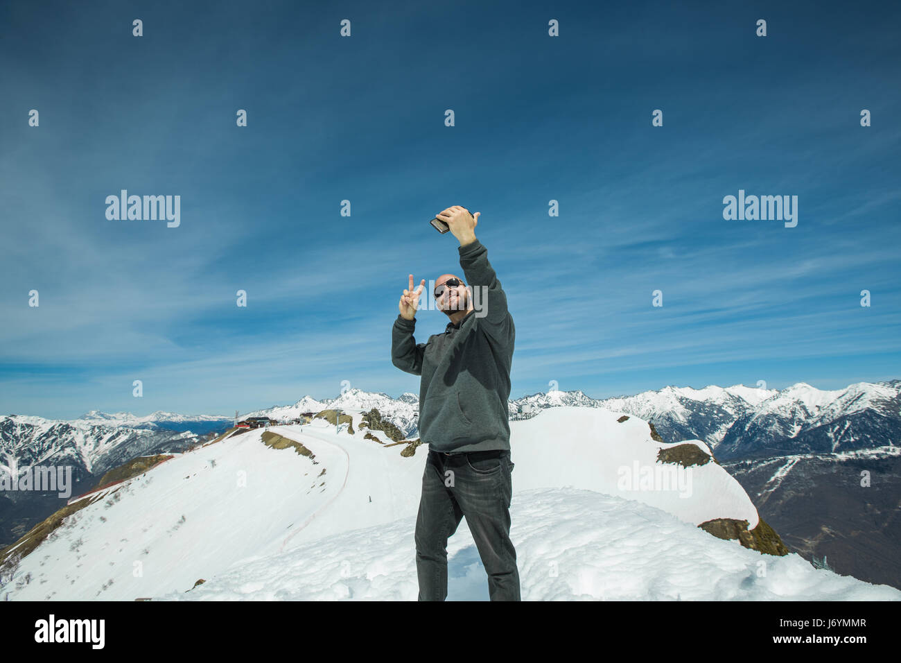 Uomo al vertice della montagna tenendo un selfie, Chamonix, Francia Foto Stock