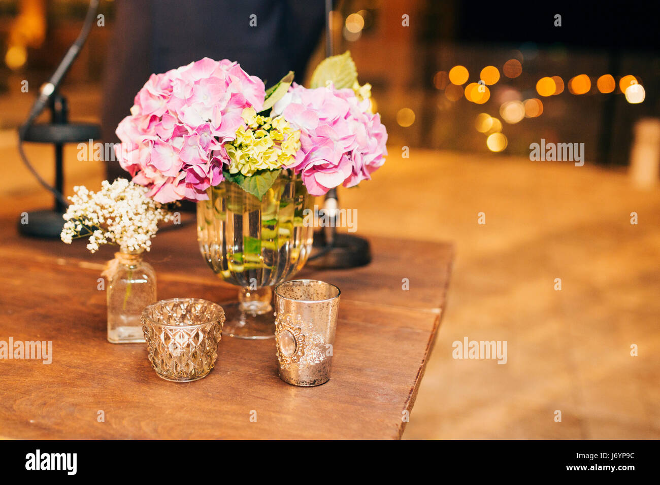 Fiori in vasi di vetro con candele sul tavolo di legno Foto Stock