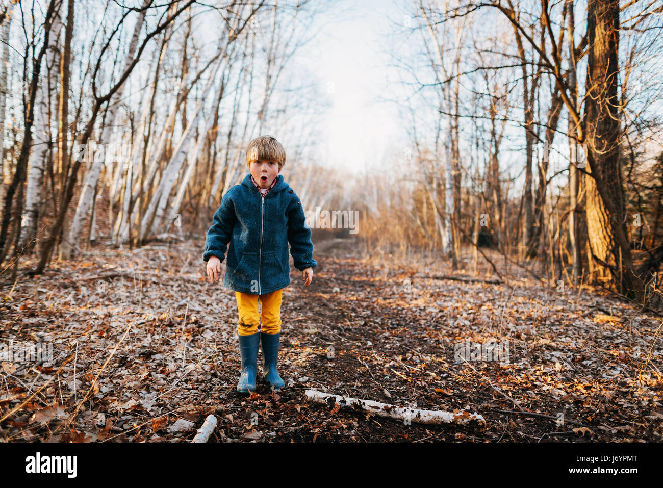 Ragazzo che sta nella foresta tirando funny faces Foto Stock