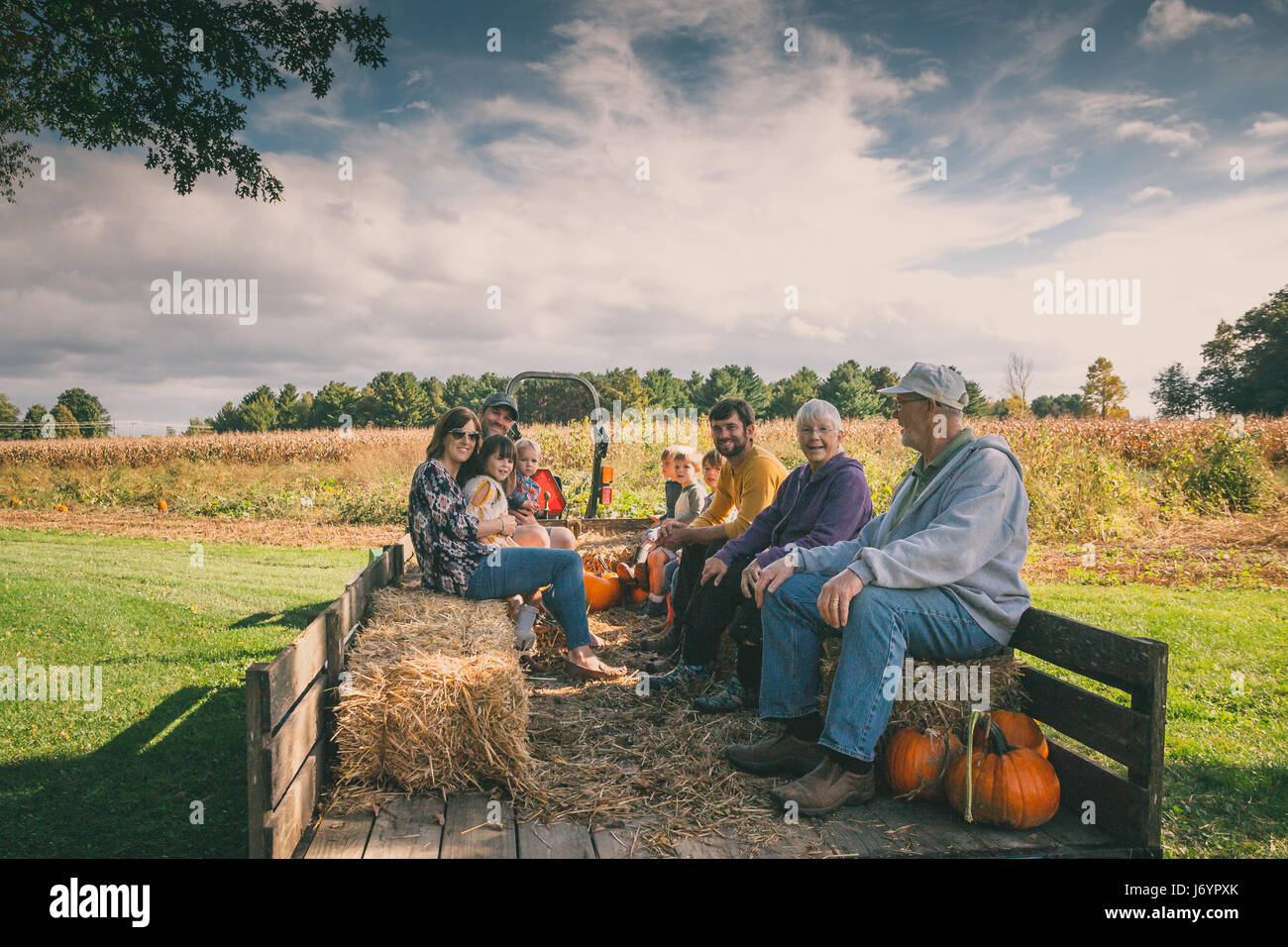 Multi-generazione famiglia seduta in un carro in un orto di zucche Foto Stock