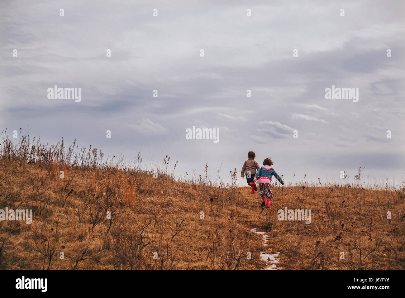 Due bambini in esecuzione su per una collina Foto Stock