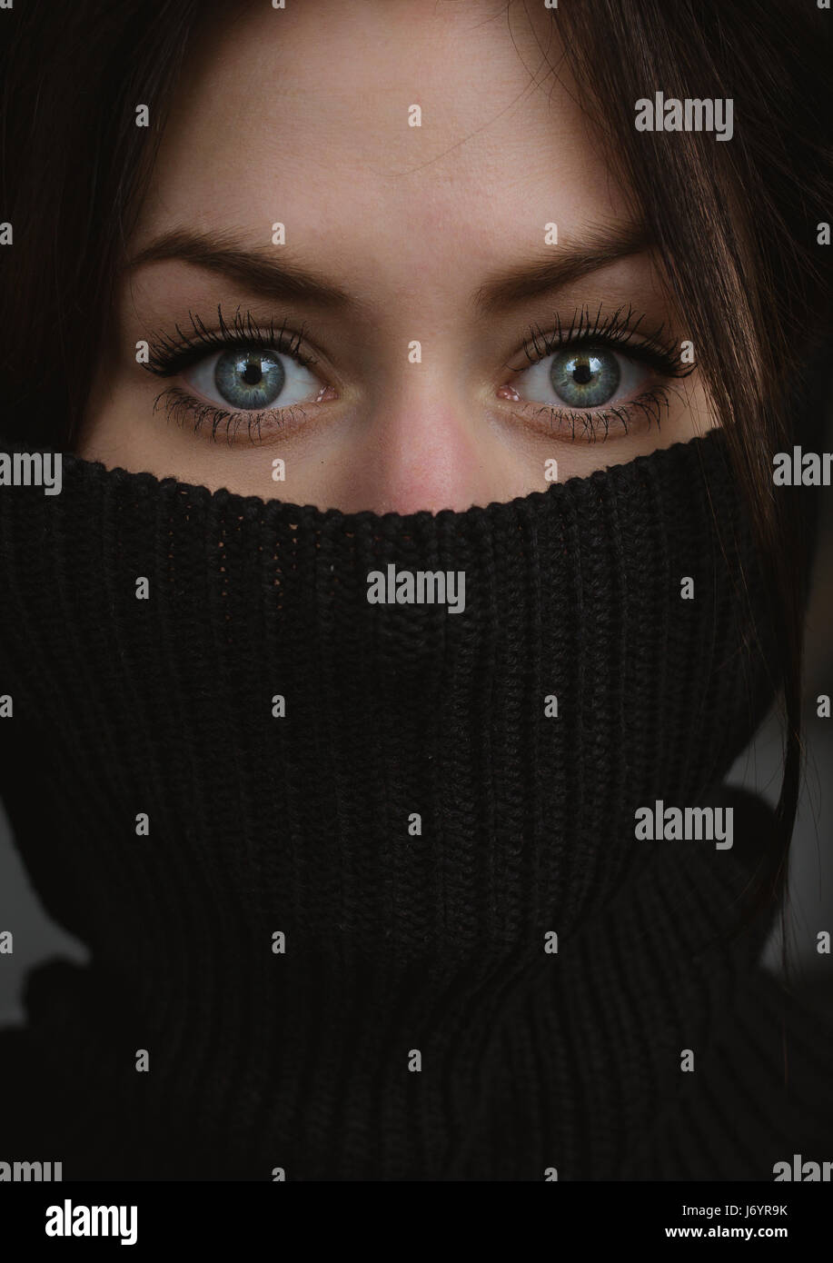 Ritratto di una donna con un ponticello turtleneck che copre la bocca Foto Stock