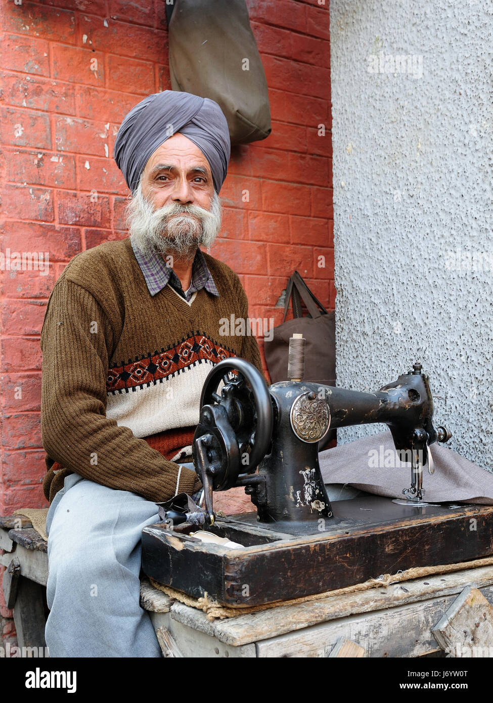 INDIA, AMRITSAR - 02 dicembre 2009: sarto con la macchina da cucire vestiti di riparazione nelle strade delle città indiane Foto Stock