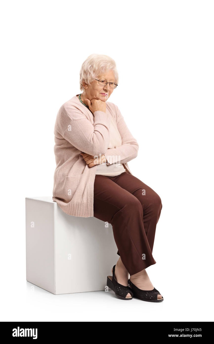 Triste donna matura seduto su un cubo isolato su sfondo bianco Foto Stock