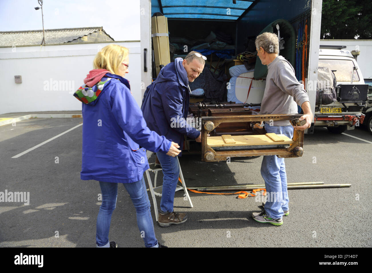 Distacco uomini tenendo vittoriana di legno di quercia hall stand da impianto di stoccaggio e di caricamento su autocarro Surrey in Inghilterra Foto Stock