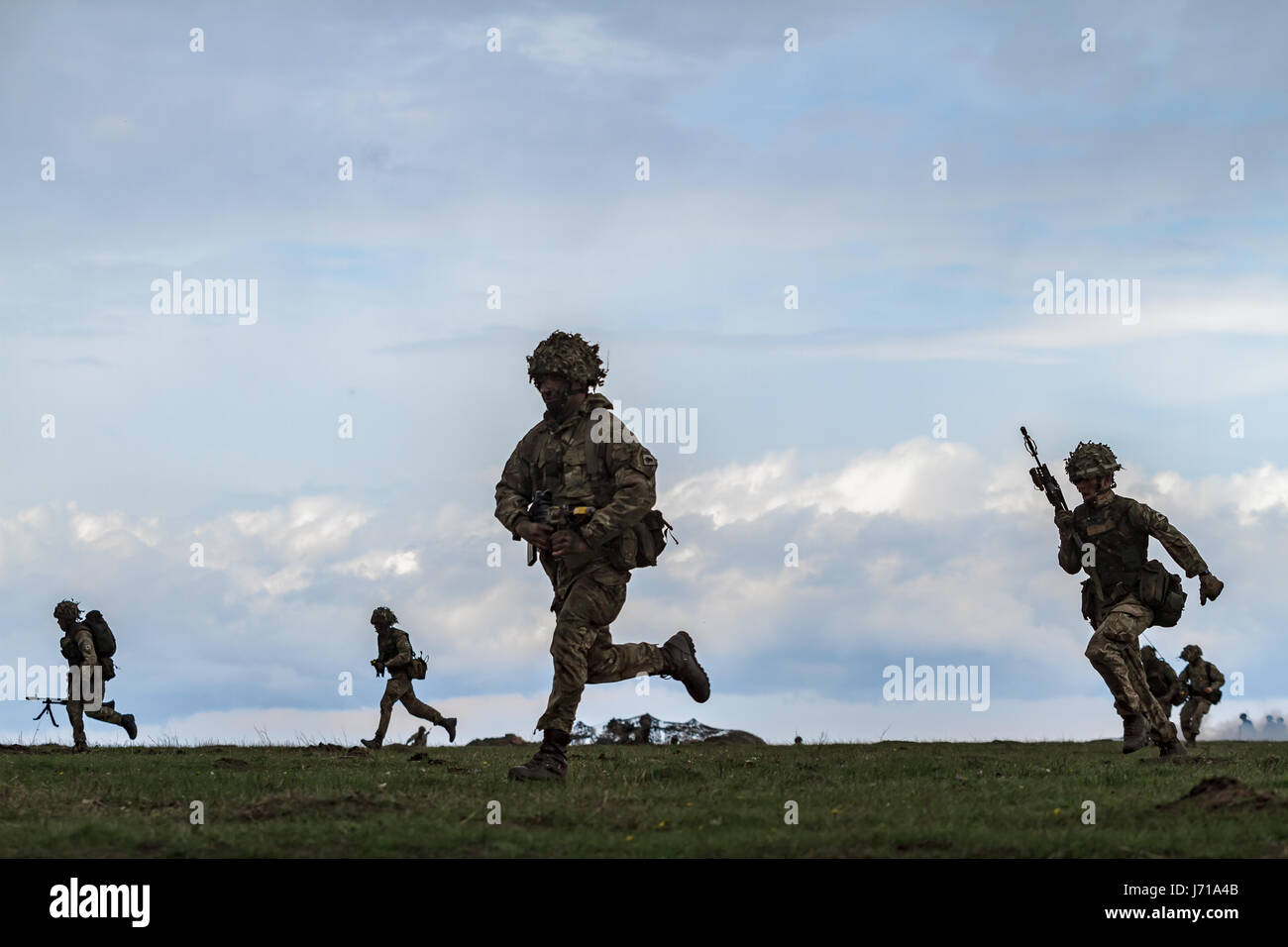 I soldati britannici corrono per una nuova posizione mentre sono difesi da un carro armato rumeno e da un elicottero d'attacco durante il trivello militare NATO 'Wind Spring -15' al poligono di tiro di Smardan Foto Stock