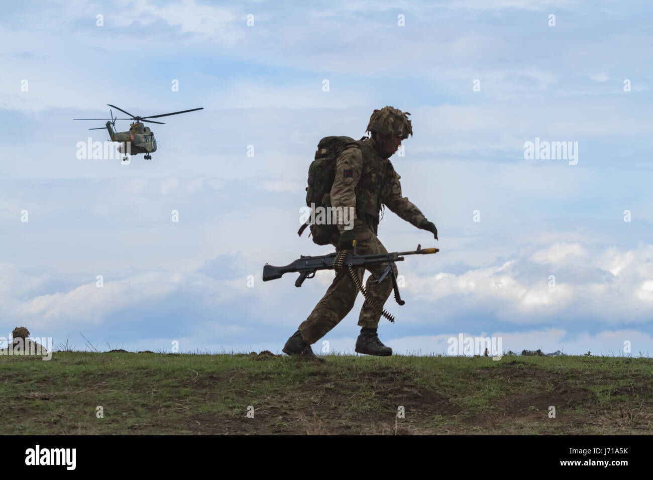 I soldati britannici corrono per una nuova posizione mentre sono difesi da un carro armato rumeno e da un elicottero d'attacco durante il trivello militare NATO 'Wind Spring -15' al poligono di tiro di Smardan Foto Stock