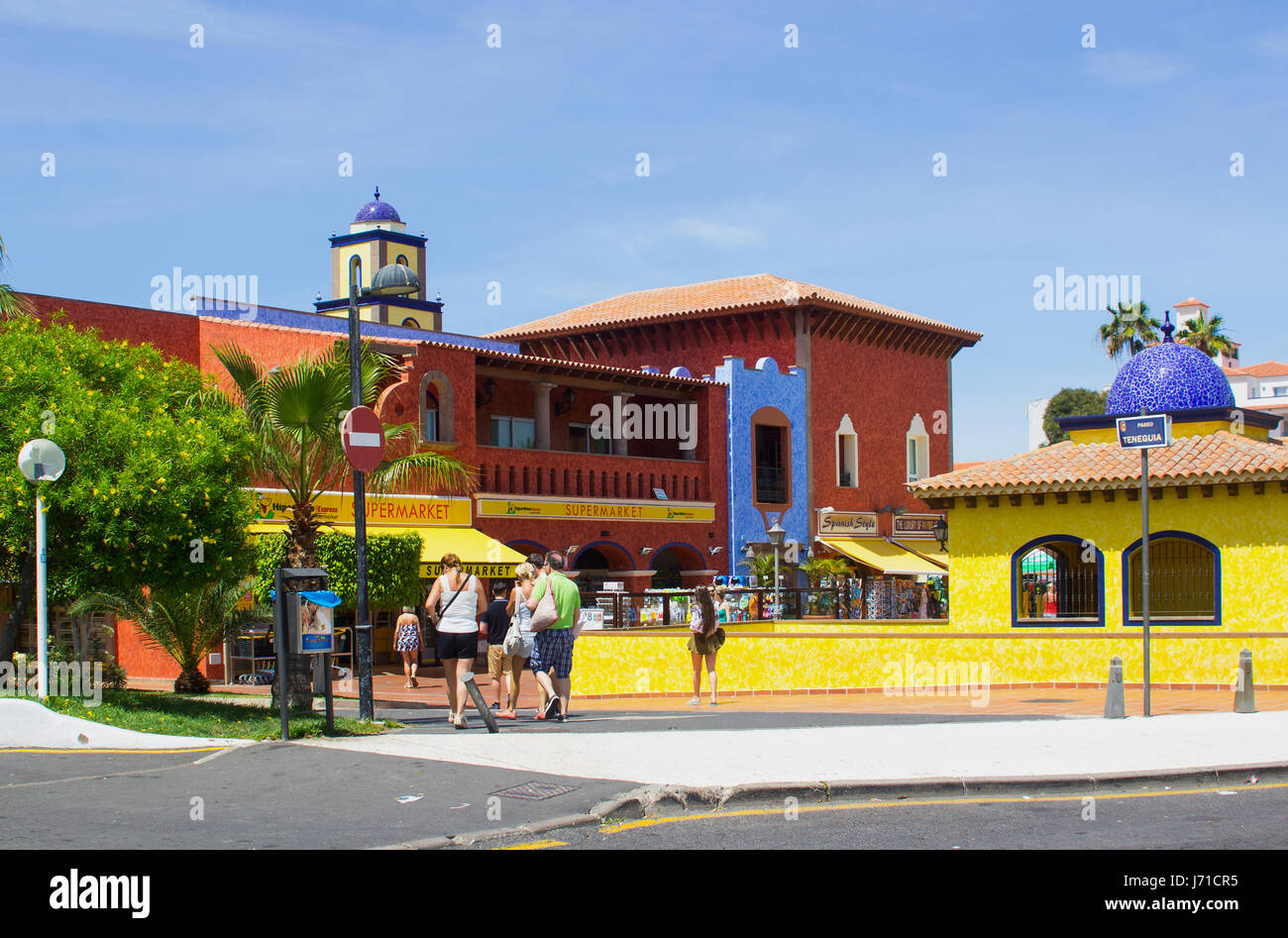 Turisti visitano il centro commerciale locale con la sua architettura distintivo su una calda giornata di sole in Playa Las Americas in Teneriffe Foto Stock