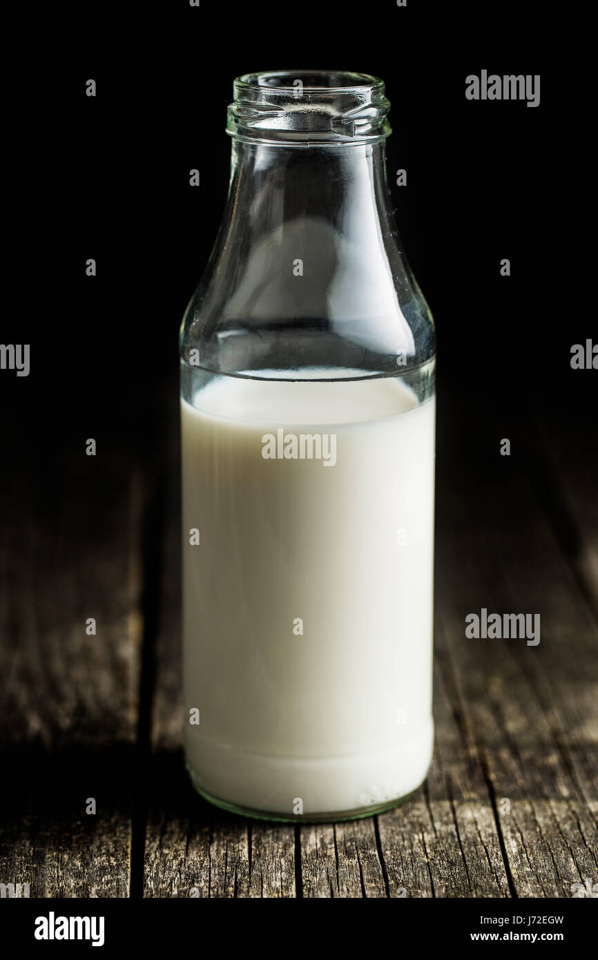 Bottiglia di latte sul vecchio tavolo in legno. Foto Stock