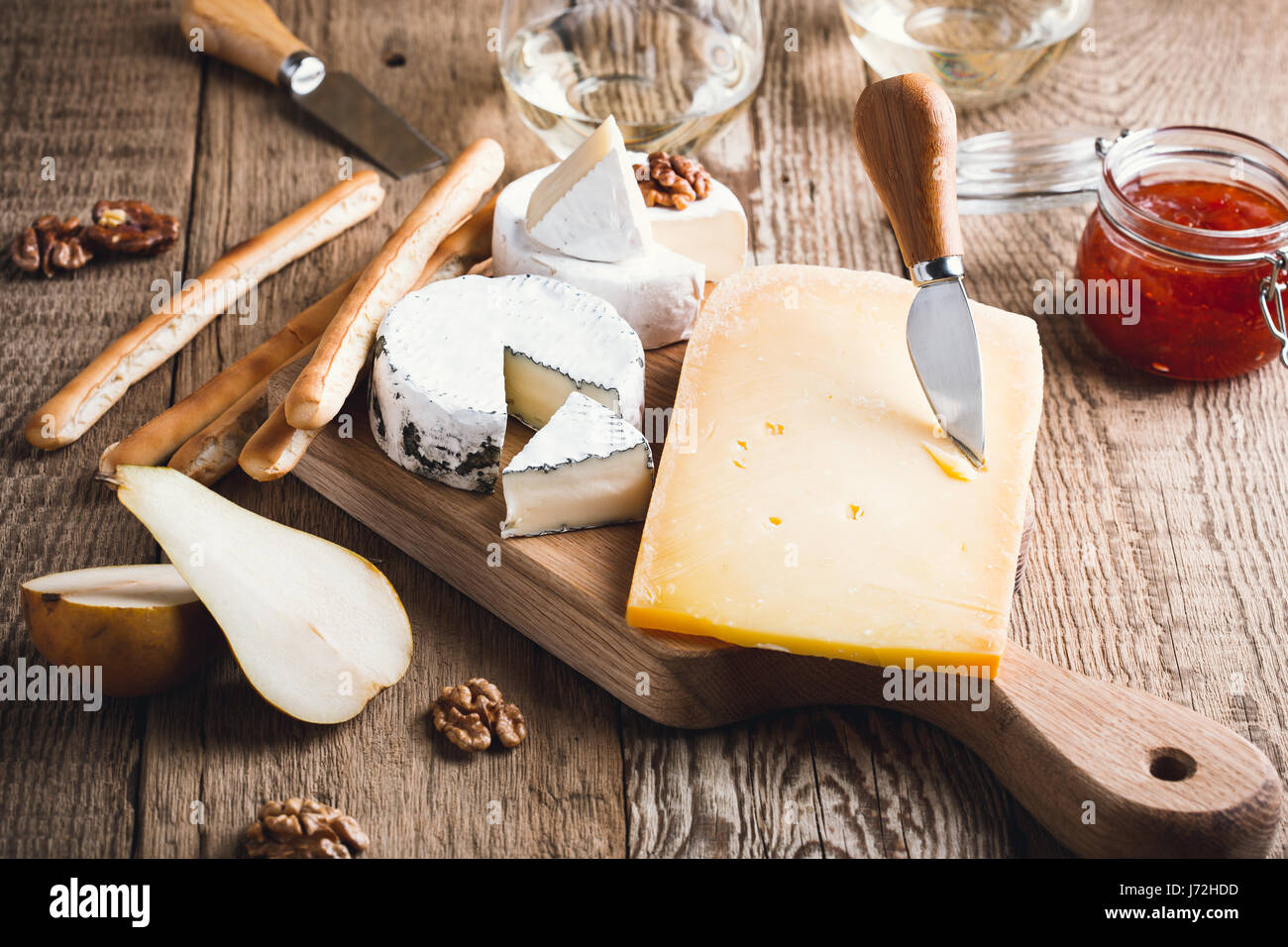 Vassoio di formaggi serviti con vino bianco, marmellata e noci su tavola di legno sul tavolo rustico Foto Stock