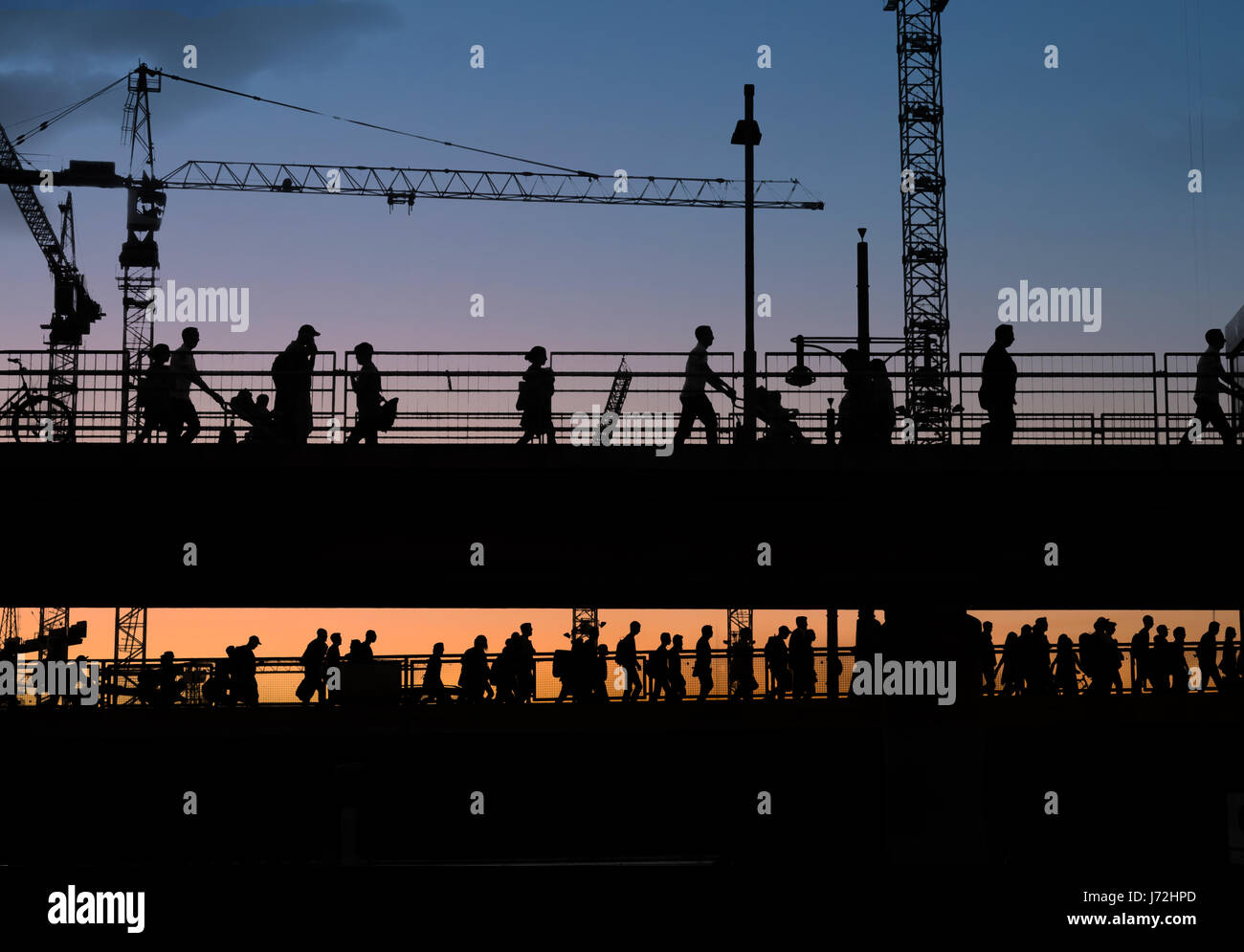 Sagome di molte persone attraversando ponte con Cielo di tramonto sullo sfondo Foto Stock