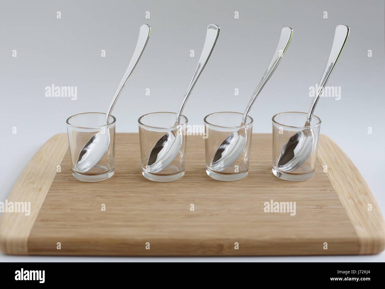 Un set di quattro piccoli contenitori in vetro e cucchiai, pronti per una prova di degustazione. Foto Stock