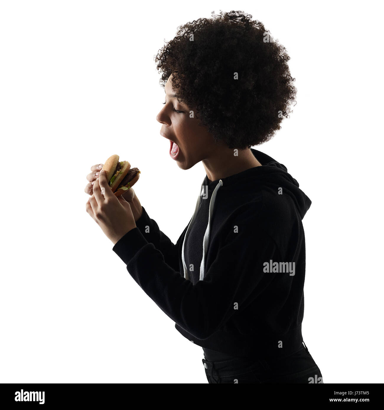 Una razza mista africana di adolescente Ragazza donna mangiare hamburger in studio ombra silhouette isolati su sfondo bianco Foto Stock