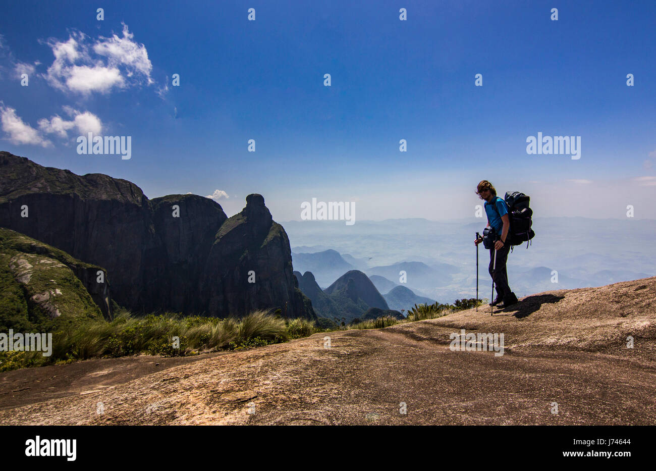 Uomo con zaino in piedi sulla cima della montagna con il cielo blu con nuvole Foto Stock