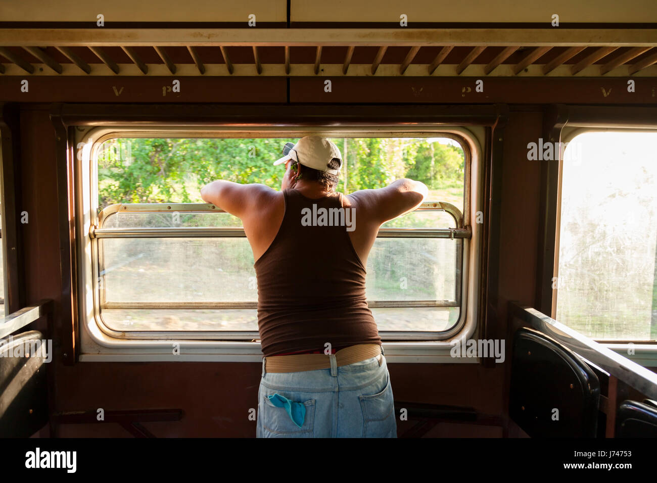 Un uomo che guarda fuori una finestra del treno a Cuba. Foto Stock