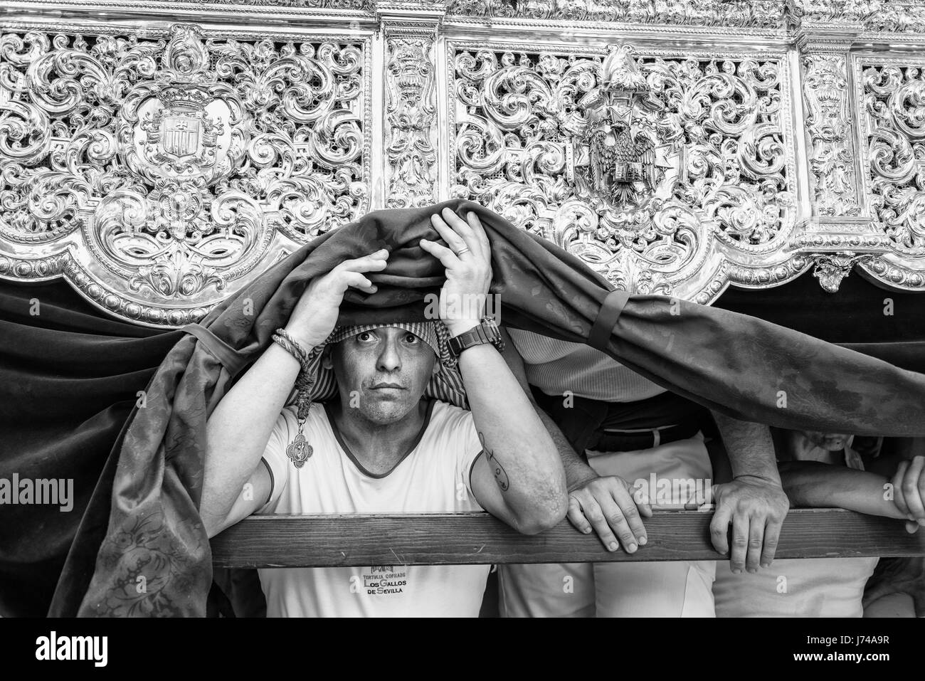 Costalero guardando fuori da sotto l'immagine sta portando durante una pausa nella processione."Costaleros' sono le persone incaricate di effettuare il Foto Stock