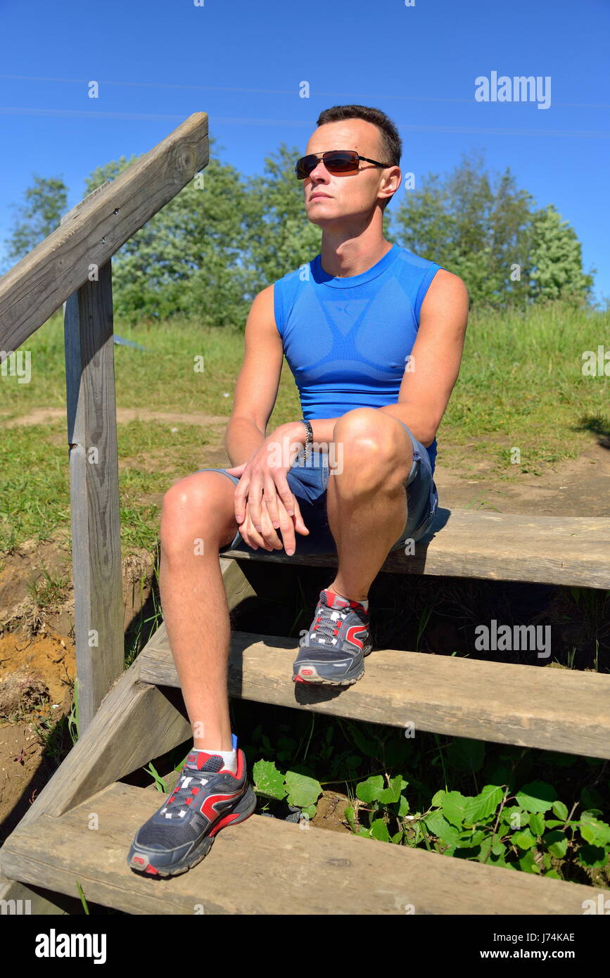 Un giovane uomo si siede sui gradini in legno sulla riva . Foto Stock