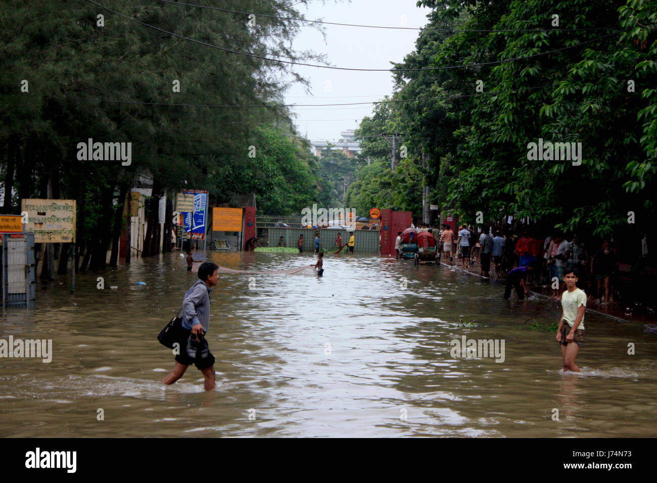 I giovani cercano di net pesce su una strada principale dopo un monsone torrenziale acquazzone ha lasciato molte parti basse della città subacquea. Dacca in Bangladesh. Foto Stock