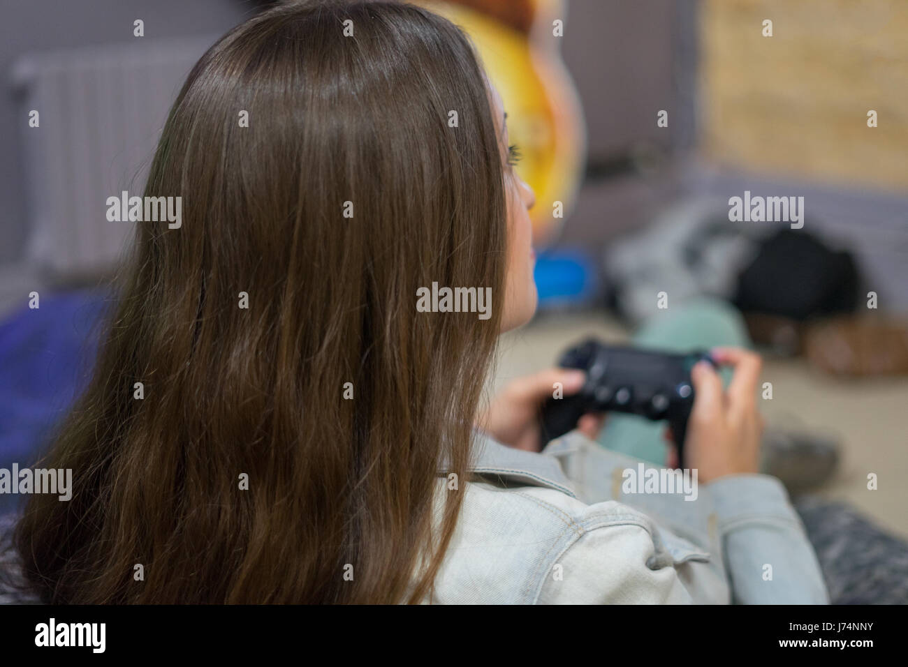 Ragazza del giocatore di giocare con i videogiochi con joystick seduto sulla poltrona sacco Foto Stock