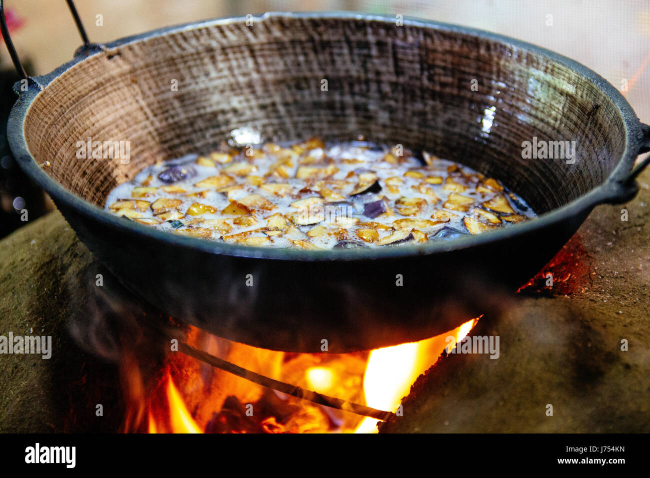 Verdure fritte essendo oltre a legna per la stufa fatta di fango e argilla in un esterno tradizionale dello Sri Lanka la cucina. Foto Stock