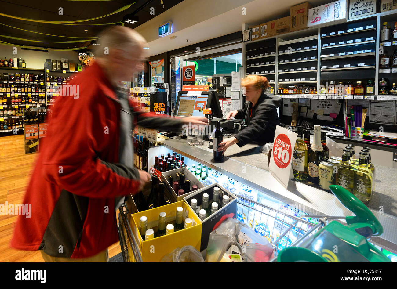 Il cliente pagando in bottiglia BWS Shop counter, Kiama, Nuovo Galles del Sud, NSW, Australia Foto Stock