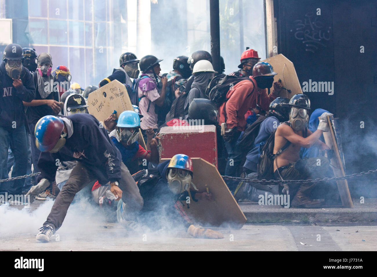 I manifestanti tentano di prendere un gas lacrimogeni barattolo sparati dalla polizia durante una manifestazione di protesta contro il governo di nicolas maduro a Caracas. Foto Stock