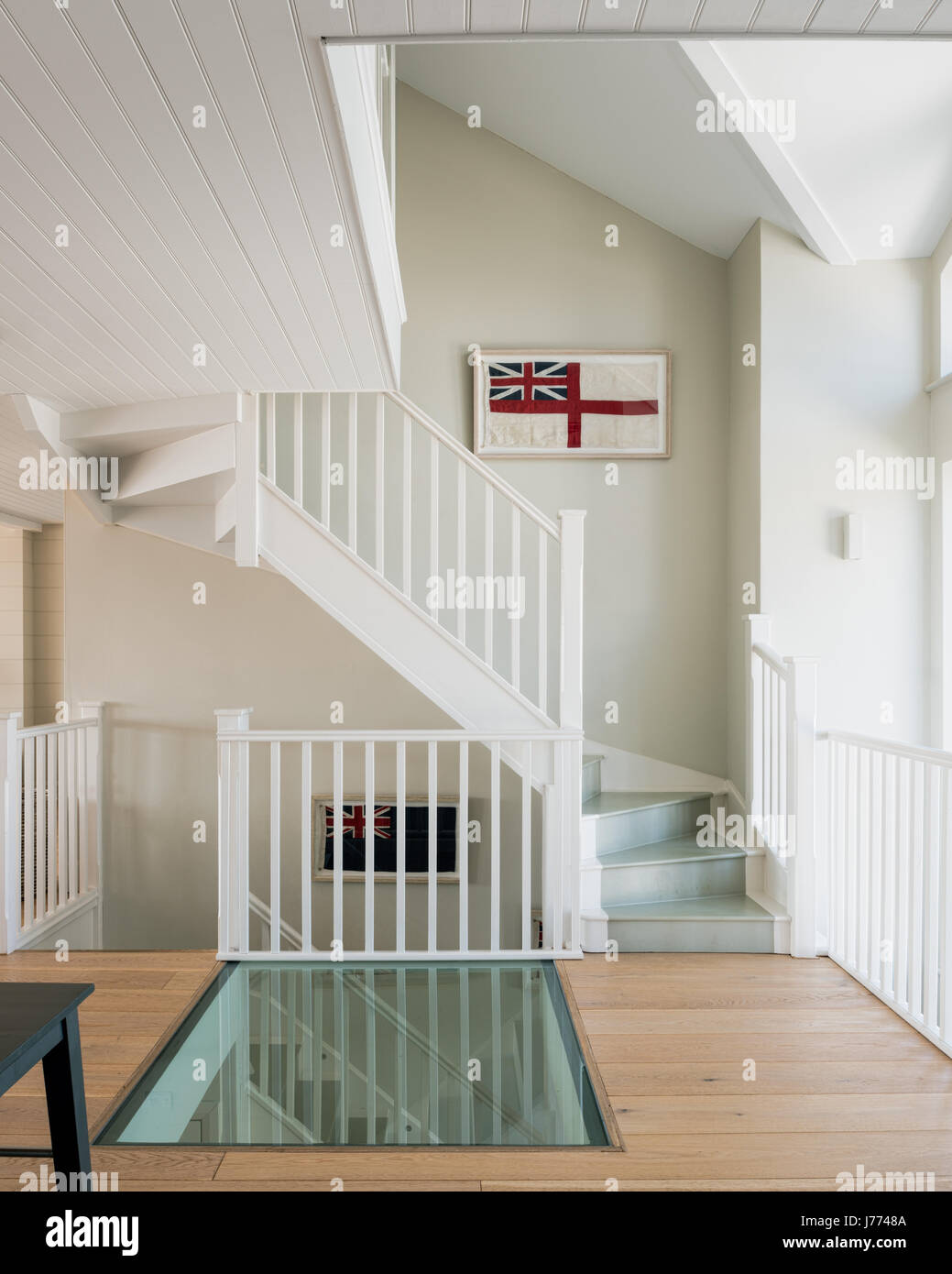 Pavimento in vetro su primi piani di sbarco con incorniciato vecchie bandiere britanniche lungo la scalinata. Le pareti sono dipinte in grigio del cappello da Sanderson. Foto Stock