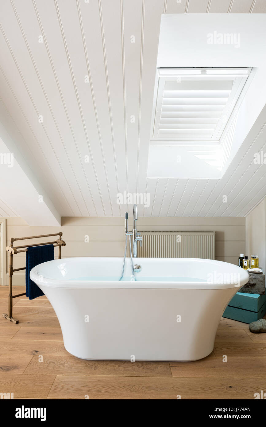 Free standing bath in piano superiore camera da letto padronale con soffitto spiovente e persiane. Foto Stock