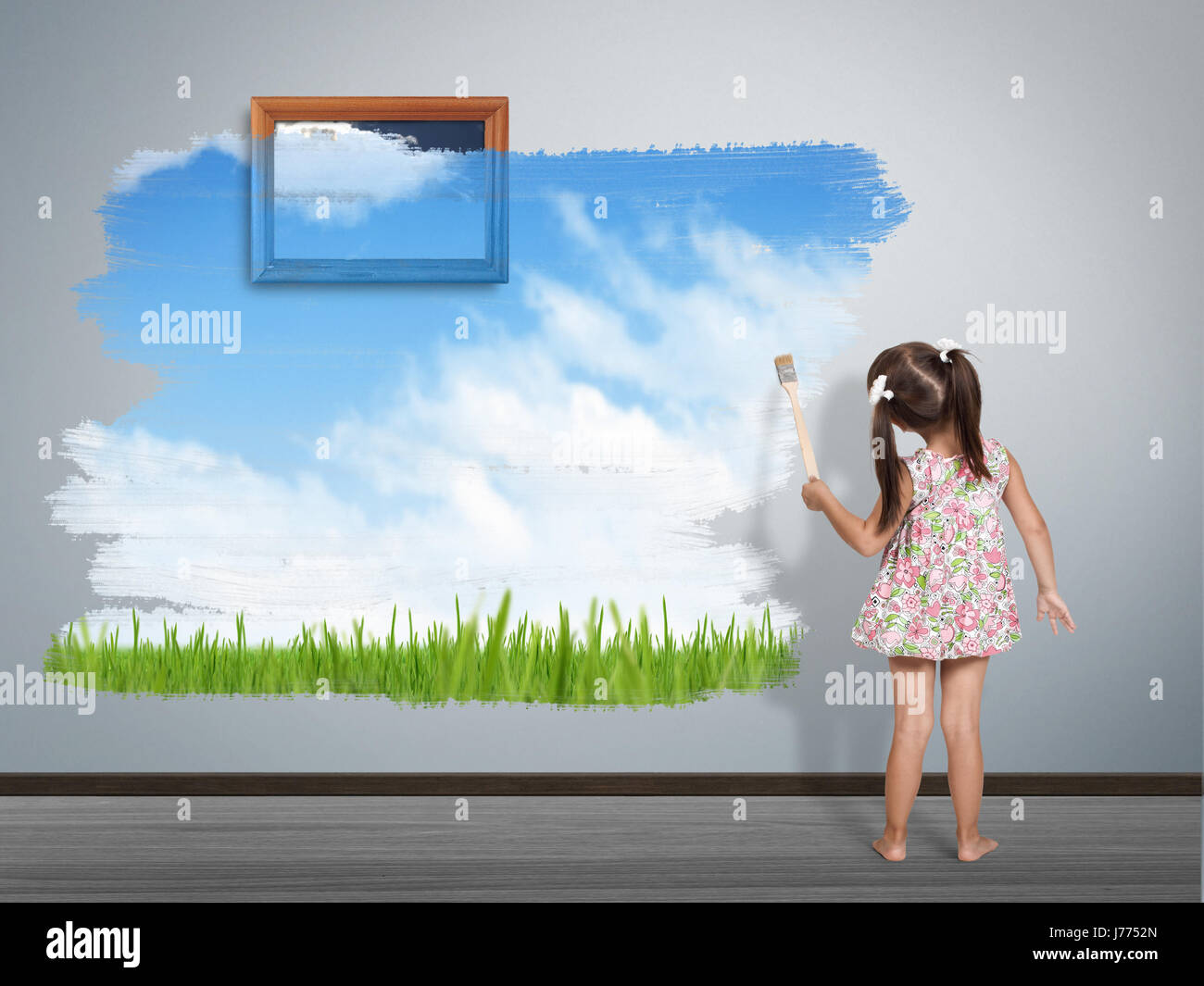 Bambino ragazza con spazzola di vernice pittura parete, vista posteriore Foto Stock
