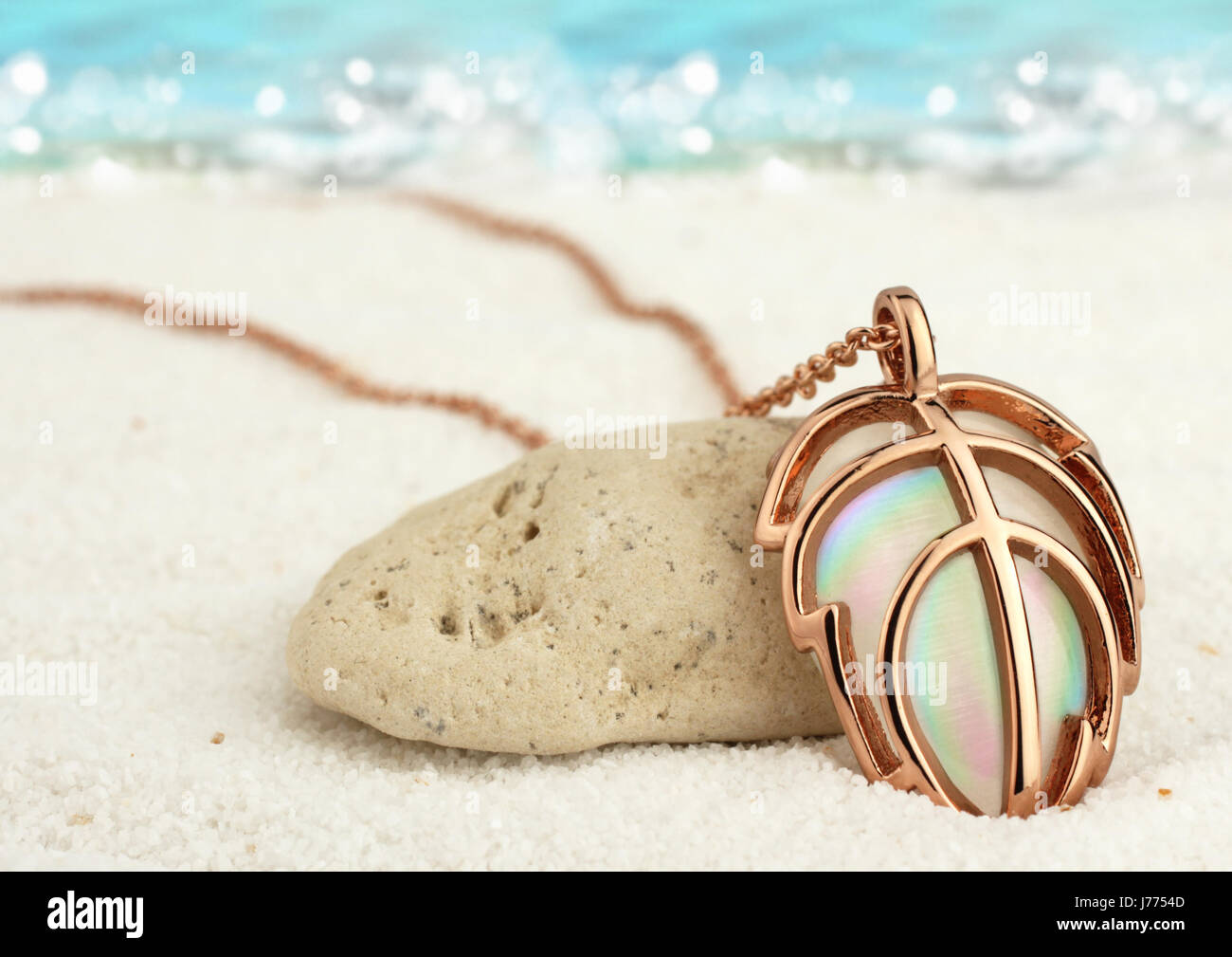 Gioielli in Oro, pendente in estate la spiaggia di sabbia con lo sfondo del mare, soft focus Foto Stock
