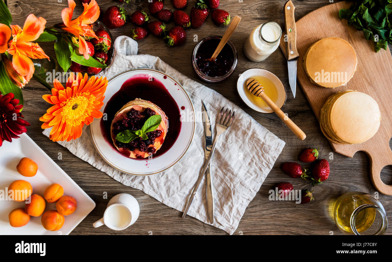 Vista superiore della pila in casa american pancake con la marmellata di fragole e su sfondo di legno. Foto Stock