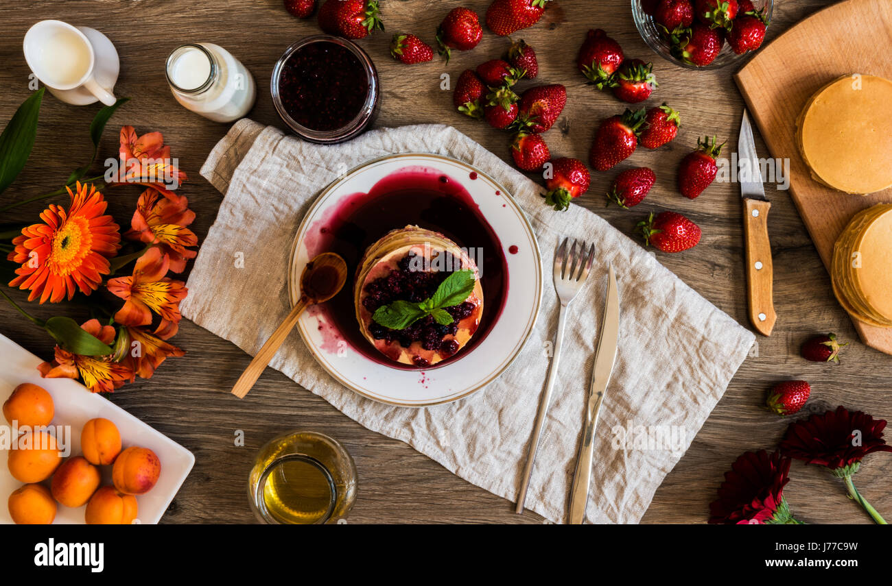 Vista superiore della pila in casa american pancake con la marmellata di fragole e su sfondo di legno. Foto Stock