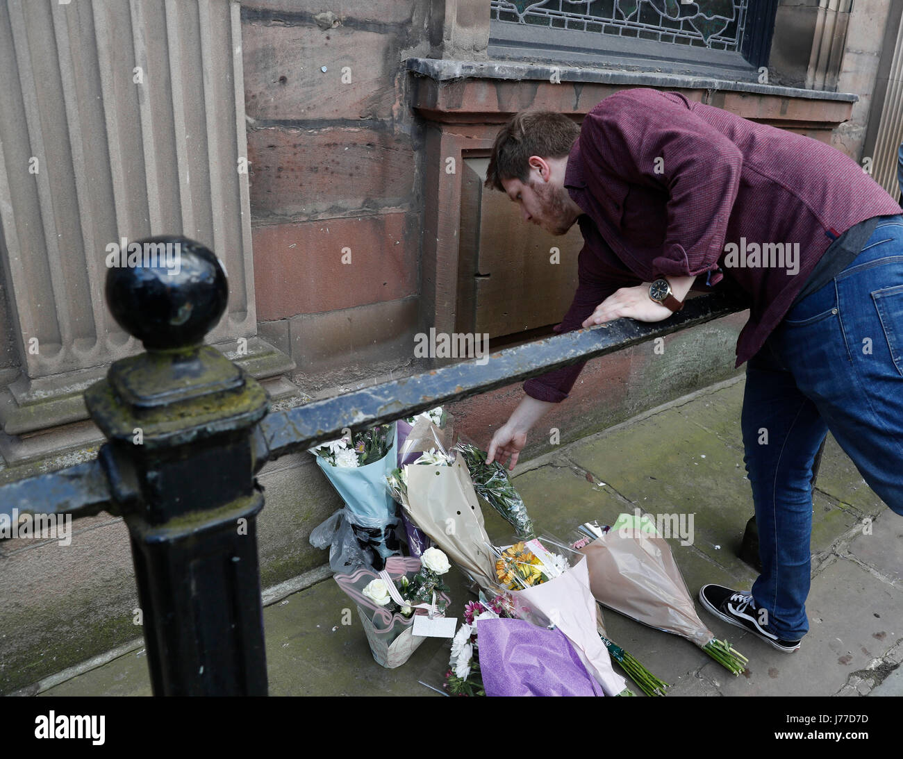 Manchester, Regno Unito. 23 Maggio, 2017. Un uomo getta fiori in memoria delle vittime del Manchester Arena bombardamenti in Manchester, Regno Unito, 23 maggio 2017. Un totale di 22 persone, compresi bambini, sono stati uccisi e 59 altri feriti in un attentato attacco terroristico a Manchester Arena lunedì sera, la polizia ha annunciato martedì. Credito: Han Yan/Xinhua/Alamy Live News Foto Stock