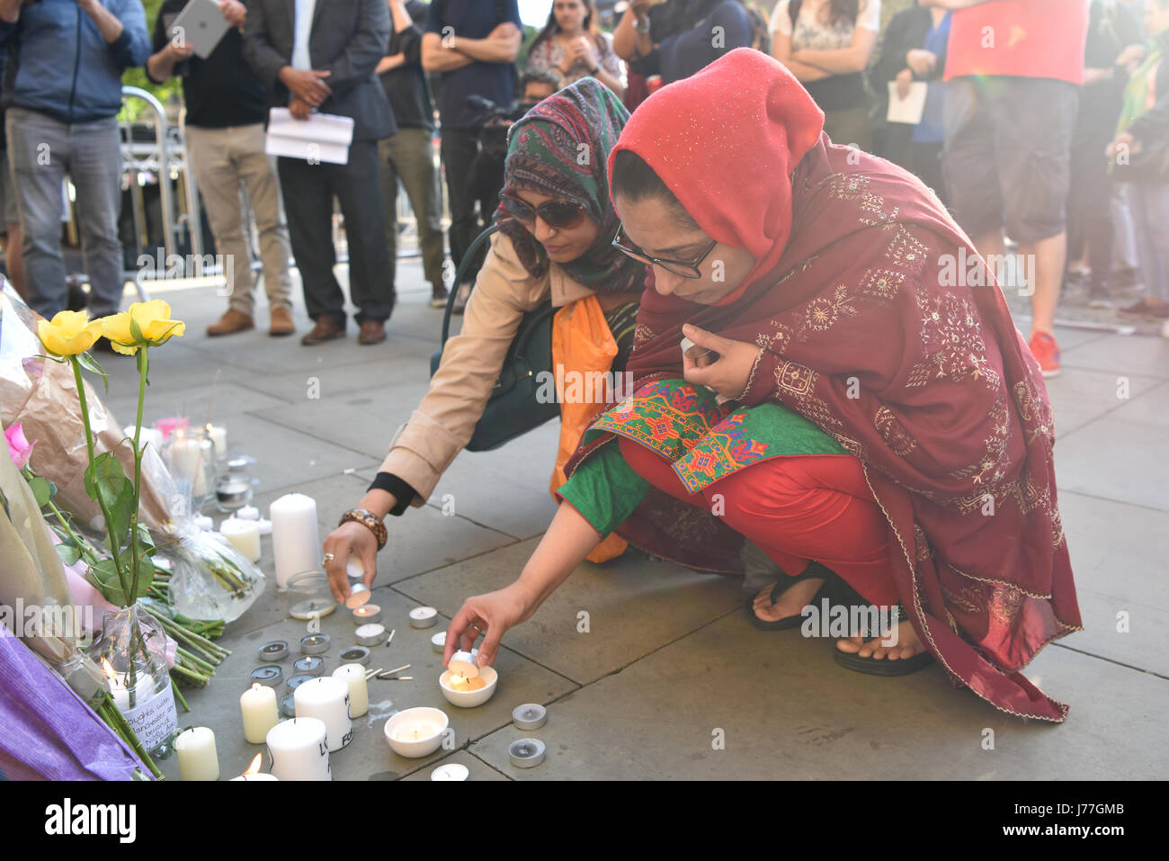 Manchester, Regno Unito. 23 Maggio, 2017. Due donne che accendono le candele in Manchester Albert Square alla fine di una veglia di pagare rispetto a seguito dell'attacco terroristico su Manchester Stadium. Il sindaco di Manchester Andy Burnham, Home Secretary Ambra Rudd, leader laburista Jeremy Corbyn e Lib Dem leader Tim Farron, accanto a città e fede leader erano tra coloro che hanno partecipato. Credito: Giacobbe Sacks-Jones/Alamy Live News. Foto Stock