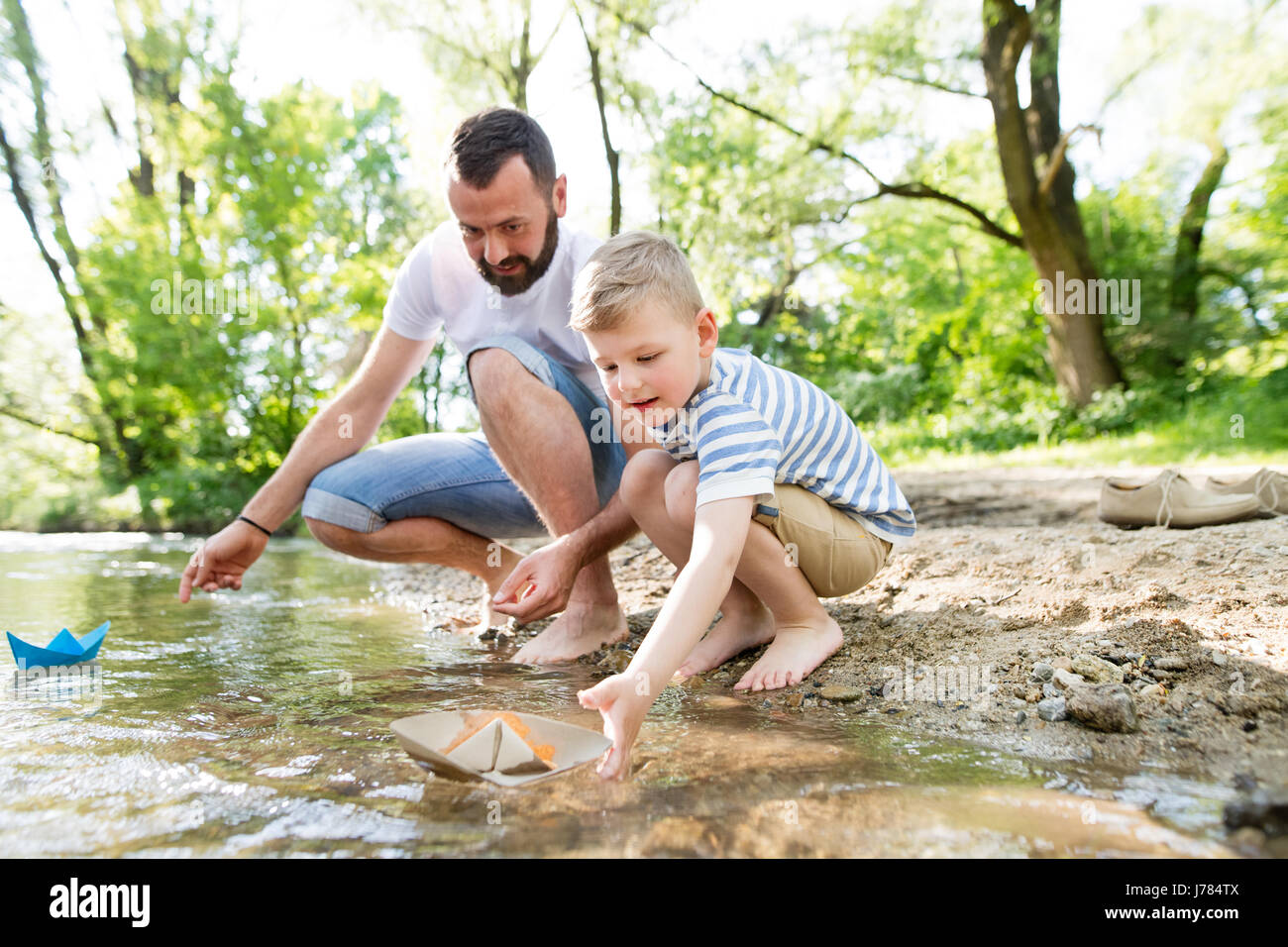 Giovane padre con little boy presso il fiume, soleggiata giornata di primavera. Foto Stock